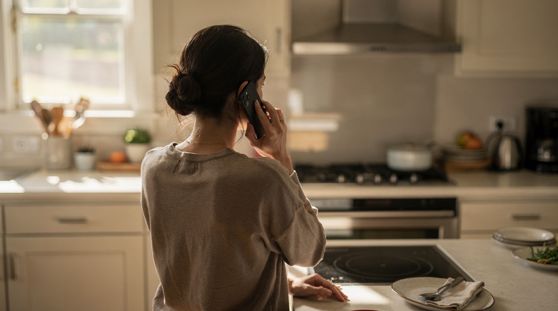 Personne au téléphone en train de déclarer un sinistre à son assureur depuis sa cuisine